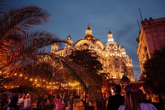 Centraal Station in Antwerpen sfeervol verlicht met architecturale accenten en bezoekers op het plein.
