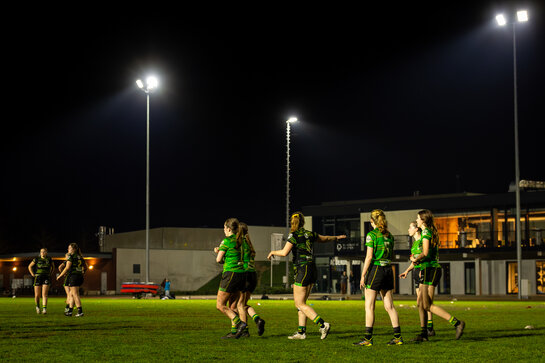 Groep sporters actief op een terrein onder felle verlichting tijdens de nacht.
