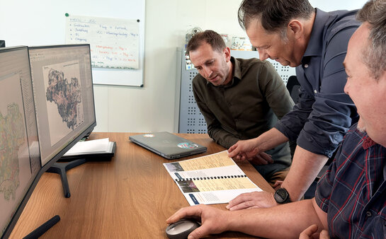 Overleg over geïntegreerd verlichtingsplan in Bonheiden Medewerkers overleggen rond een tafel en analyseren een verlichtingsplan met kaarten en documentatie voor het masterplan openbare verlichting in Bonheiden.