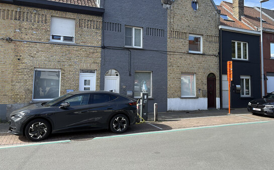 Waar komen de laadpalen? Publieke laadpaal in woonstraat met geparkeerde elektrische wagen in Roeselare.