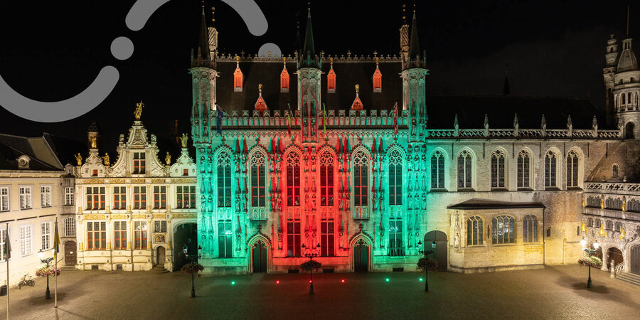 Stadhuis in Brugge, sfeervol verlicht op de Grote Markt bij avond.
