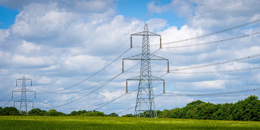 Netcongestie flexibel oplossen: wat betekent dat voor je stad of gemeente? Hoogspanningslijnen in landschap illustreren druk op elektriciteitsnet en netcongestie.