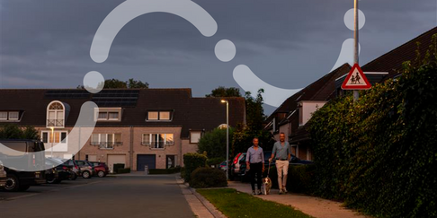 Residentiële straat in de schemering met brandende led-straatverlichting en voorbijgangers, als voorbeeld van verledding bij lokale besturen.