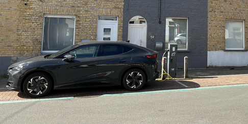 Publieke laadpaal in het straatbeeld van Roeselare met een elektrische wagen die aan het opladen is.