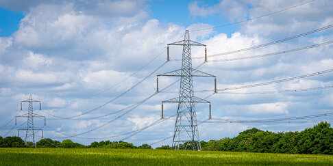 Hoogspanningslijnen in landschap illustreren druk op elektriciteitsnet en netcongestie.